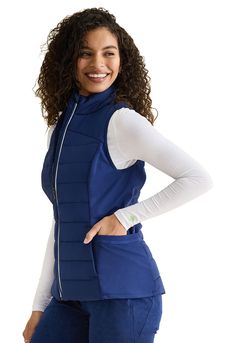 The Mixed Media Quilted Vest has a zip front with reflective trim and a Healing Hands logo zipper pull. This flattering vest features quilted front and back panels. Tonal knit side panels provide comfort and stretch. There is a total of seven pockets for organized storage: two front zipper pockets, two side pockets, two inside pockets, and a media pocket. Rib-knit trim at the top of side pockets provides extra design interest. Water-resistant, Teflon-coated fabric. Length: 25.5". Collection : HH Limited EditionFit : ModernJacket Length : MediumClosure : Zip FrontNumber of Pockets : 7 PocketsTypes of Pockets : Cell Phone Pocket, Interior Pocket, Zip Front Pocket, Side Panel Pocket, No Chest PocketFeatures : Knit Details, Quilted, Front shoulder yokeManufactured In : Imported Fitted Quilted Nylon Vest, Stretch Outerwear With Zipper Closure For Outdoor Activities, Fitted Sleeveless Functional Outerwear, Sporty Fitted Vest For Outdoor, Winter Stretch Nylon Vest, Fitted Nylon Sporty Vest, Sporty Fitted Nylon Vest, Functional Fitted Nylon Vest, Fitted Functional Nylon Vest