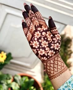 a woman's hand with henna on it and flowers in the back ground