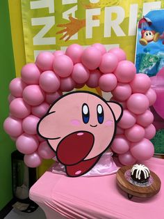 a pink table topped with lots of balloons and a cartoon character on top of it