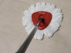 a person using a mop on the floor to clean it with a red handle