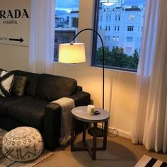 a living room filled with furniture and a lamp on top of a table next to a window