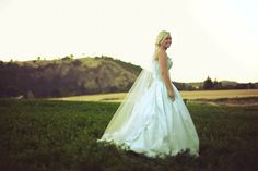 a woman in a wedding dress standing in the grass