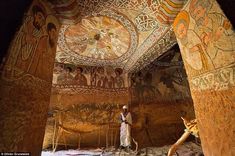 a man standing in the middle of a room with paintings on the walls and ceiling