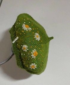 a green hat with daisies on it sitting on a white surface next to a computer mouse