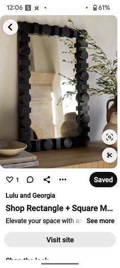 a mirror sitting on top of a wooden table next to a vase with plants in it