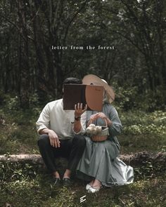 a man and woman sitting in the grass with a book on their head, both looking at each other