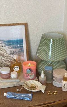 an assortment of personal care items on a table next to a framed photograph and lamp