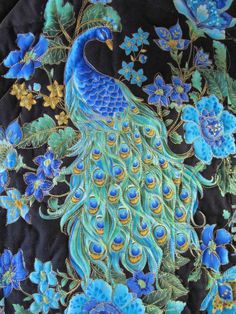 a blue and green peacock with flowers on it's back side is featured in this close up photo