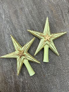 two green star shaped objects sitting on top of a wooden table next to each other