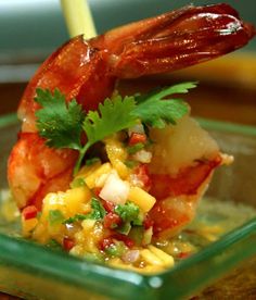 a dish with shrimp, corn and salsa in it on a wooden table next to a yellow straw