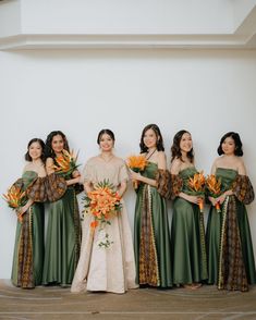 a group of women standing next to each other holding bouquets in their hands and wearing green dresses