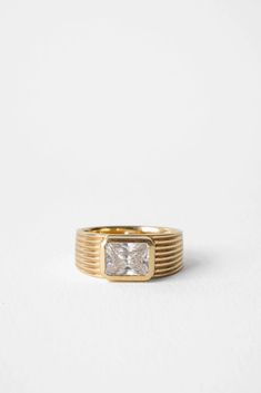 a yellow gold ring with a princess cut diamond in the center, on a white background