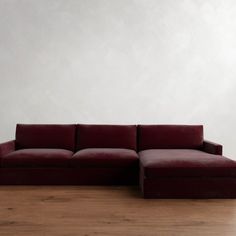 a red couch sitting on top of a hard wood floor next to a white wall