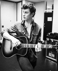 a young man is playing the guitar in an office setting, black and white photo