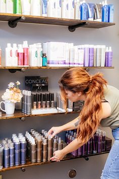 a woman is looking at the shelves with many different types of hair products on it