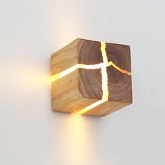 a wooden light that is on the side of a wall and has a cross cut in it