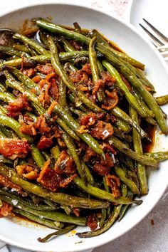 a white bowl filled with green beans and bacon