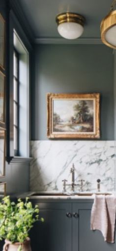 a kitchen with marble counter tops and gray cabinets, along with potted plants in vases