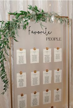 a table plan with greenery on it and seating cards attached to the board for guests