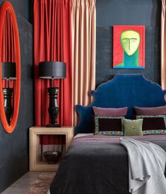 a bedroom with black walls, blue headboard and red drapes on the windows