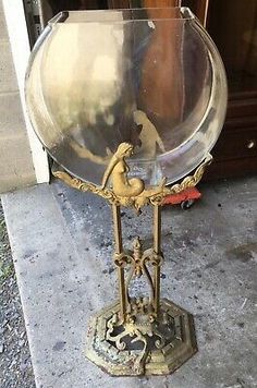 an old fashioned metal clock sitting on top of a cement floor next to a door