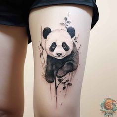 a panda bear tattoo on the thigh with flowers and leaves around its neck, in black and white