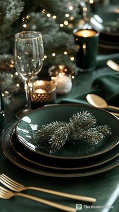 the table is set with green and gold place settings, silverware, and candles