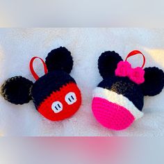 two crocheted mickey and minnie mouse hats on a white blanket with red bows