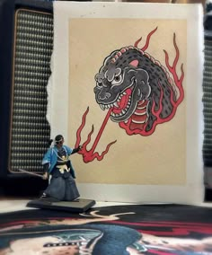 a small figurine on top of a table next to a wall with an image of a dragon