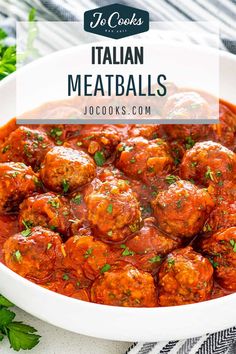 a white bowl filled with meatballs covered in sauce and garnished with parsley