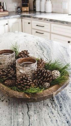 some pine cones are sitting on a wooden tray in the middle of a kitchen counter