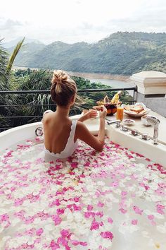 a woman sitting in a hot tub filled with flowers