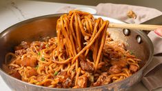 someone is stirring noodles in a pan with chopsticks