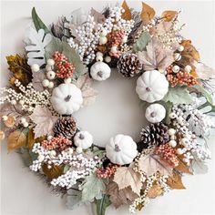 a wreath with white pumpkins, leaves and berries