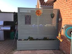 an outdoor kitchen area with grill, sink and bbq in the back ground next to a brick wall