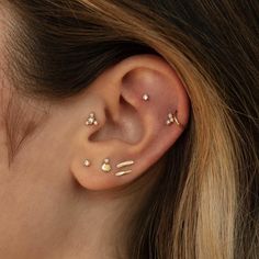 a woman's ear with three different piercings on her left side, and two smaller ones in the middle