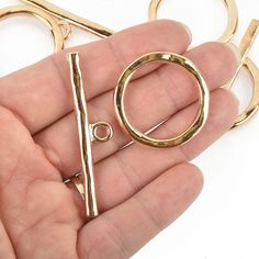 a pair of scissors being held in the palm of someone's hand with gold colored handles