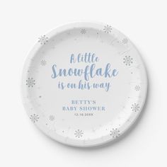 a white paper plate with blue lettering and snowflakes on the rim reads, a little snowflake is on his way betty's baby shower