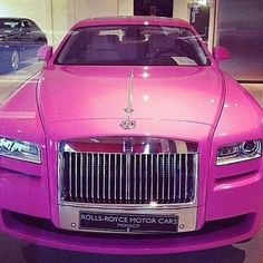 a pink rolls royce parked in a showroom