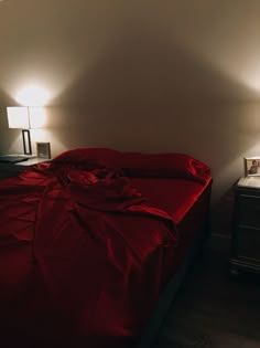 a bed with a red comforter and two lamps on either side of the bed