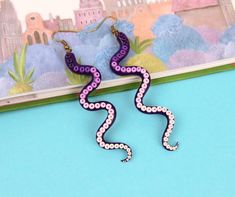 purple and white snake earrings on blue background