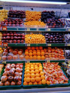 an assortment of fruits and vegetables on display in a grocery store, including oranges