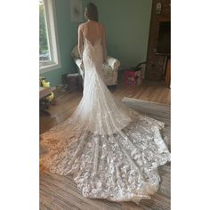 a woman in a wedding dress looking at the back of her gown, standing on a wooden floor