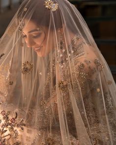 a woman wearing a wedding veil and holding a bouquet in her hands with gold sequins on it