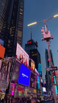 a city street filled with lots of tall buildings and billboards at night, all lit up