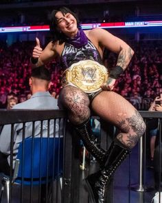 a woman in fishnet stockings and boots posing for the camera with a wrestling belt around her waist