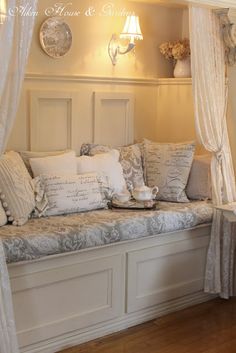 a white couch sitting under a window next to a table with a tea cup on it