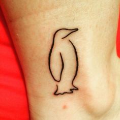 a small black and white penguin tattoo on the side of a woman's ankle