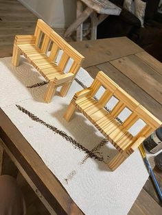 two miniature wooden benches sitting on top of a table next to a pair of scissors