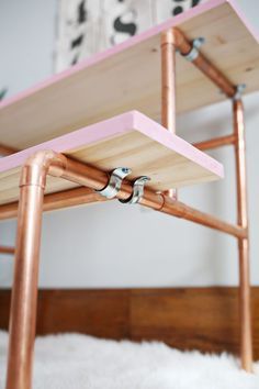 a wooden table with two metal brackets on it's sides and a white rug in the background